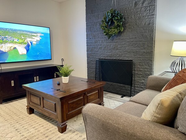 Living room with 70" TV and fireplace.