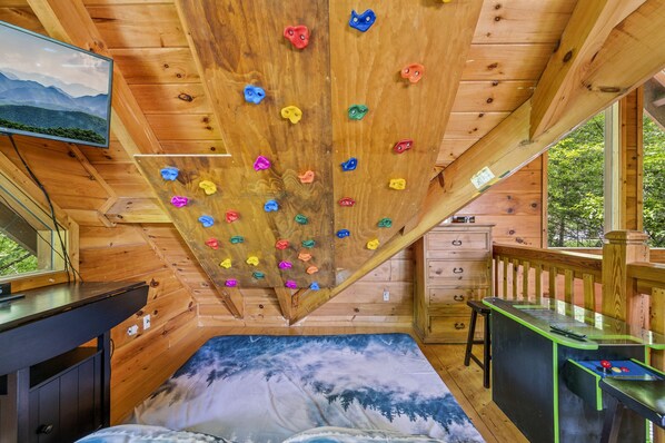 Loft area with a custom climbing wall right above a king sized mattress!