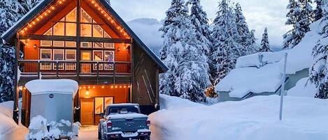 Cozy mountain chalet with warm lighting amidst a winter wonderland setting.