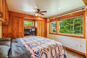 Cozy bedroom with natural wood finishes, ample lighting, and serene forest views.