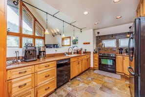 Spacious Kitchen with Natural Wood Cabinets, Modern Appliances, and Tiled Backsplash Overlooking Scenic Views