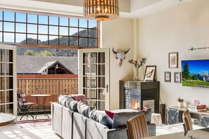 The living room opens to a balcony and french doors with mountain views.