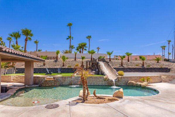Resort-style backyard oasis featuring a sparkling pool, thrilling waterslide, and desert-inspired landscaping