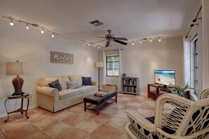 The First Family Room Has A Sofa, a Wicker Chair and a TV