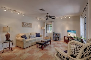The First Family Room Has A Sofa, a Wicker Chair and a TV