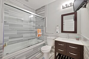 Nice clean modern bathroom with shower, jetted tub, toilet, vanity and TV.