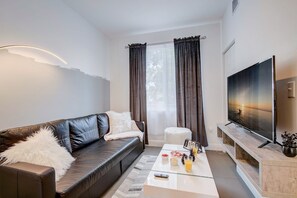 Living Room with a leather pull out couch, a Smart TV, and a closet next to it. 
