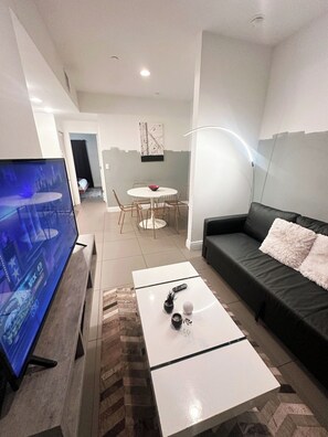Living Room with a pull out couch and a Smart TV. The dining room to the back. 