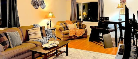 Living room with cozy accents including throw pillows, blankets, tables and lamps.
