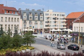 A lively city square with colorful historic buildings, greenery, and people enjoying the outdoor space, adding to the vibrant atmosphere.

