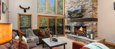 Living Room with plush furnishings, wood-burning fireplace, smart TV, and private deck access