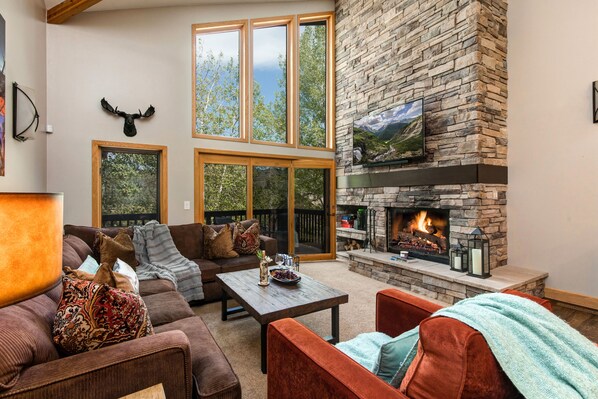 Living Room with plush furnishings, wood-burning fireplace, smart TV, and private deck access