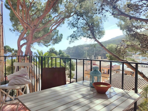 Enjoy a relaxing meal on the private balcony, with views of the sea and the charming town of Tamariu. The balcony features a white table and chairs, perfect for enjoying a morning coffee or an evening glass of wine.