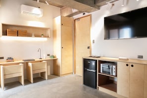 (L to R) Work desk/chair, wardrobe, fridge, microwave, 55" Smart TV, kitchenette