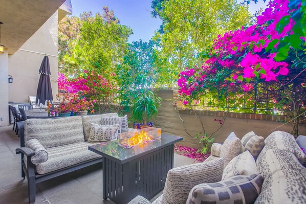 This patio has everything you need - sofas to relax on, a fire pit to keep you warm in the evening, a BBQ to grill on, and table seating for all!