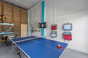 The game room has a ping pong table, foosball table and dart board
