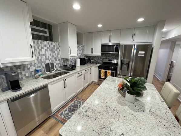 Fully stocked kitchen with full-size stainless steel appliances, and cookware.