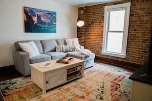 Living room with pull out sofa. Supplies are in the extended part of the couch which you can lift up to access the bedding. Games are on the coffee table shelving!