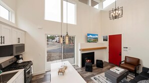 Open concept living room, dining area, and fully stocked kitchen. The living room features vaulted ceilings, a luxury queen sofa sleeper, HDTV with cable and streaming, gas fireplace, and breakfast bar seating for 3.
