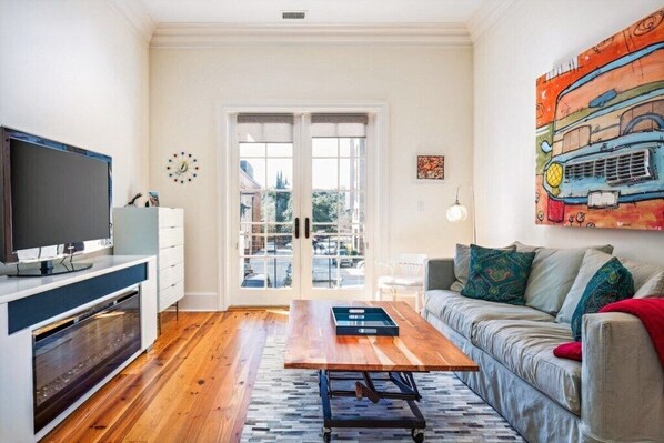 Spacious living area with French doors and warm wooden floors for a cozy, inviting feel.