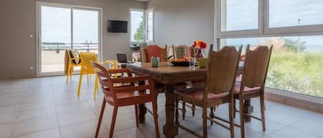 Salle à manger avec vue mer sur la terrasse puis sur la fenêtre latérale