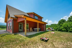 Back patio with hot tub, rocking chairs, yard games.