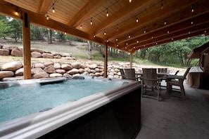 Covered outdoor patio with hot tub and lounge area with fire pit.