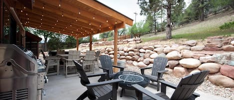Outdoor fire pit lounge area with BBQ grill, dining table and hot tub