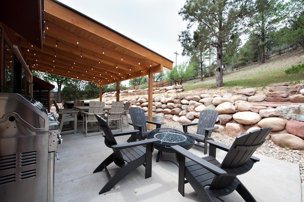 Outdoor fire pit lounge area with BBQ grill, dining table and hot tub