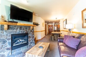 Living area with a mounted TV, stack stone gas fireplace, and sleeper sofa.