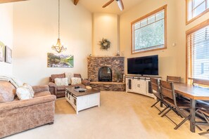 Living area featuring vaulted ceilings, a ceiling fan, cozy furnishings, and a gas fireplace.