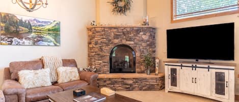 Living area featuring vaulted ceilings, a ceiling fan, cozy furnishings, and a gas fireplace.