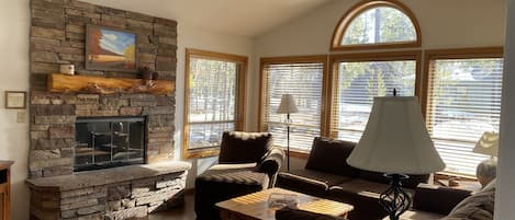 Living room with stone gas fireplace and large front windows