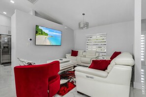 Open main living area with 70 inch tv, premium white-leather Italian furniture.