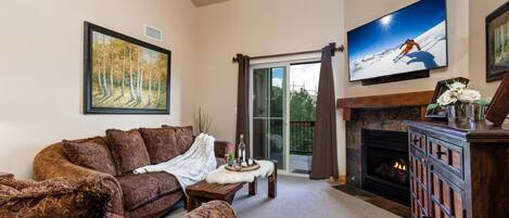 Living Room with plush sofa & loveseat, gas fireplace, 50" TV, and private deck access