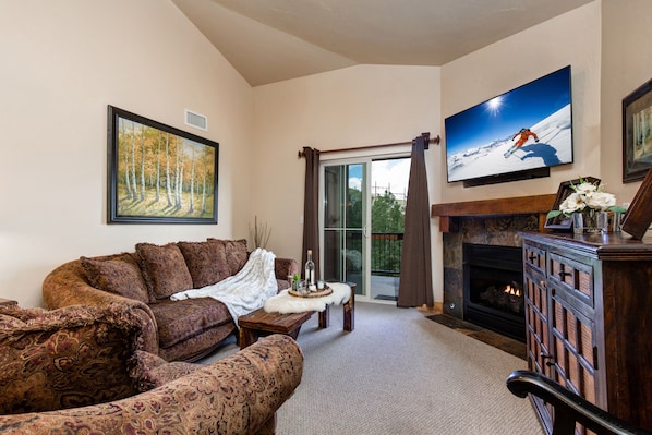 Living Room with plush sofa & loveseat, gas fireplace, 50" TV, and private deck access