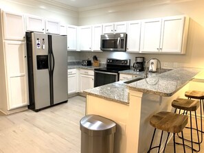 Kitchen with granite counter and seating for 3 at the breakfast bar.