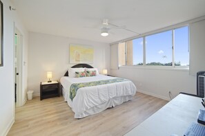 Sleep in comfort in the spacious master bedroom featuring a king-sized bed, elegant decor, and large windows offering natural light and tropical views.