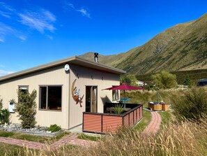 The cottage by day with stunning views of the Ben Ōhau mountain range.