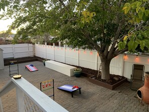 Outdoor patio with corn hole, ladder toss, chiminea, seating and outdoor lights.