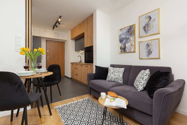 A cozy and modern living area with a fold-out gray sofa above which there are paintings hanging that add style to the room.