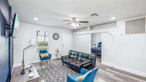 This small living room features a comfortable couch, a TV for your entertainment, and a ceiling fan to keep the space cool.