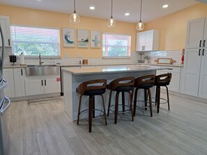 Large kitchen with new cabinets, countertops, and backsplash and island with seating for 4