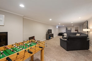 The lower level features a lounge space that doubles as a game room, providing ample space for everyone to unwind.