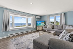 Living room, with sleeper sofa, and stunning unobstructed views of the ocean. DISCLAIMER - this couch has been swapped out. The new couch is slightly larger, a darker grey and has a Queen sleeper (instead of a full).