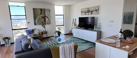 Living room with a large TV, board games and a view of the bay.