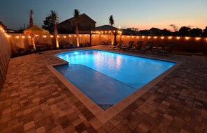 Serene landscaping and lights around the pool for an evening escape.