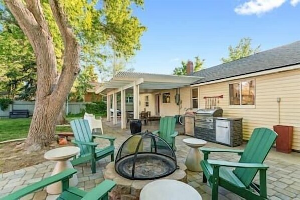 The private fenced yard offers a fire-pit, outdoor kitchen, and comfortable seating for gatherings.