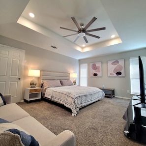 Primary bedroom with king bed, sofa, and tv