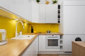 A modern kitchen with bright yellow backsplash, white cabinetry, and wooden countertops for a clean, vibrant look.
